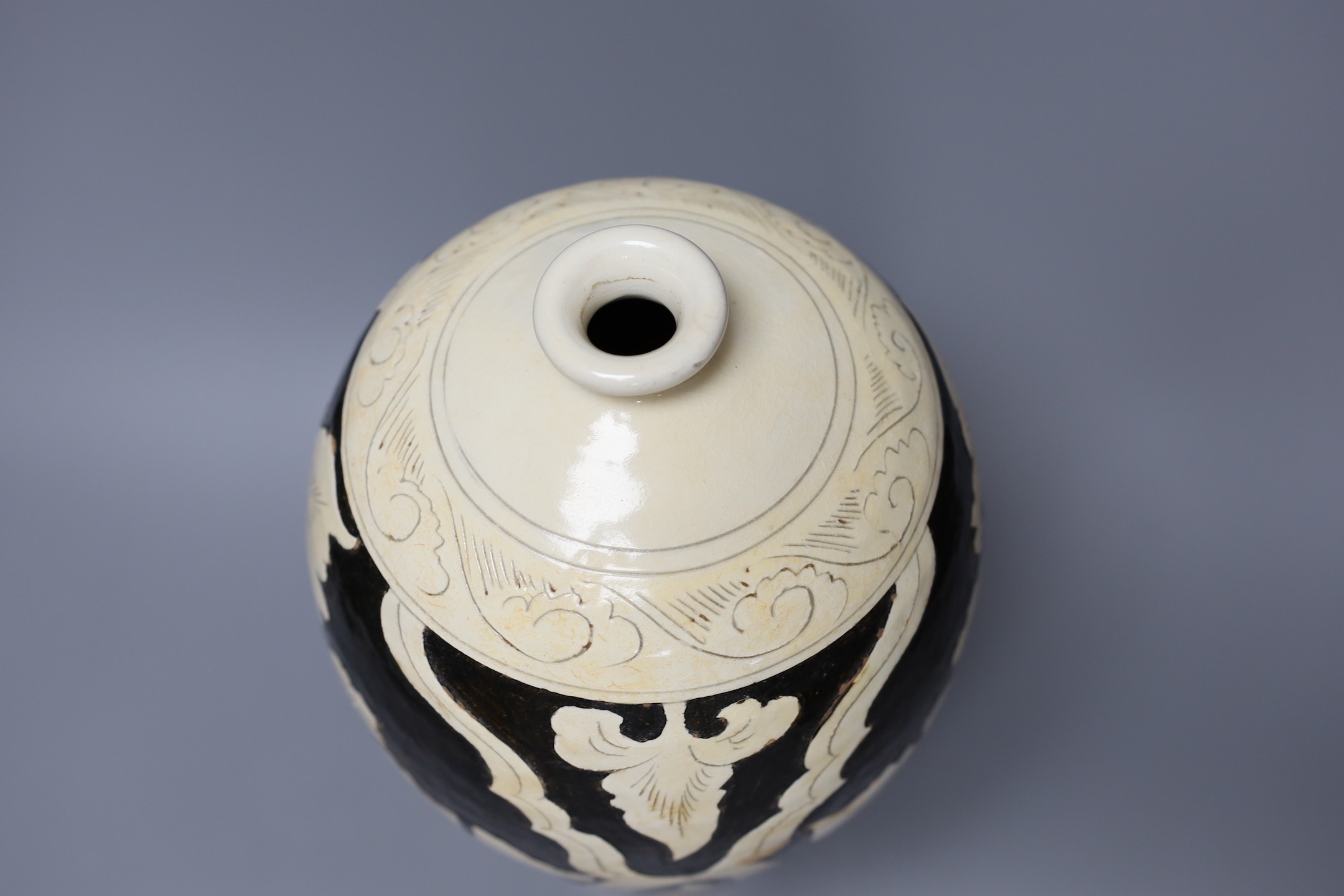 A black and white carved Chinese peony earthenware vase, 34cm tall